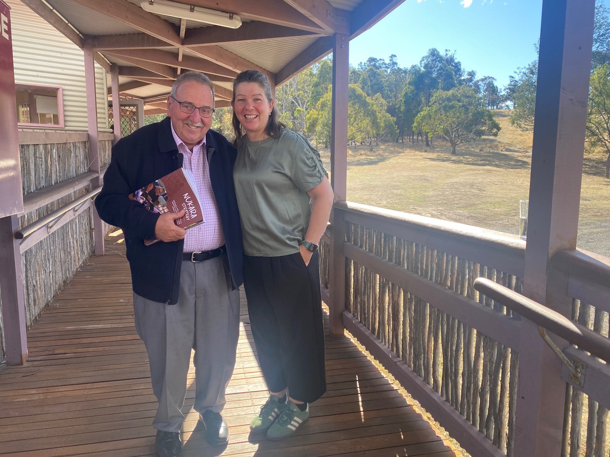 man with booklet and woman standing on a verandah